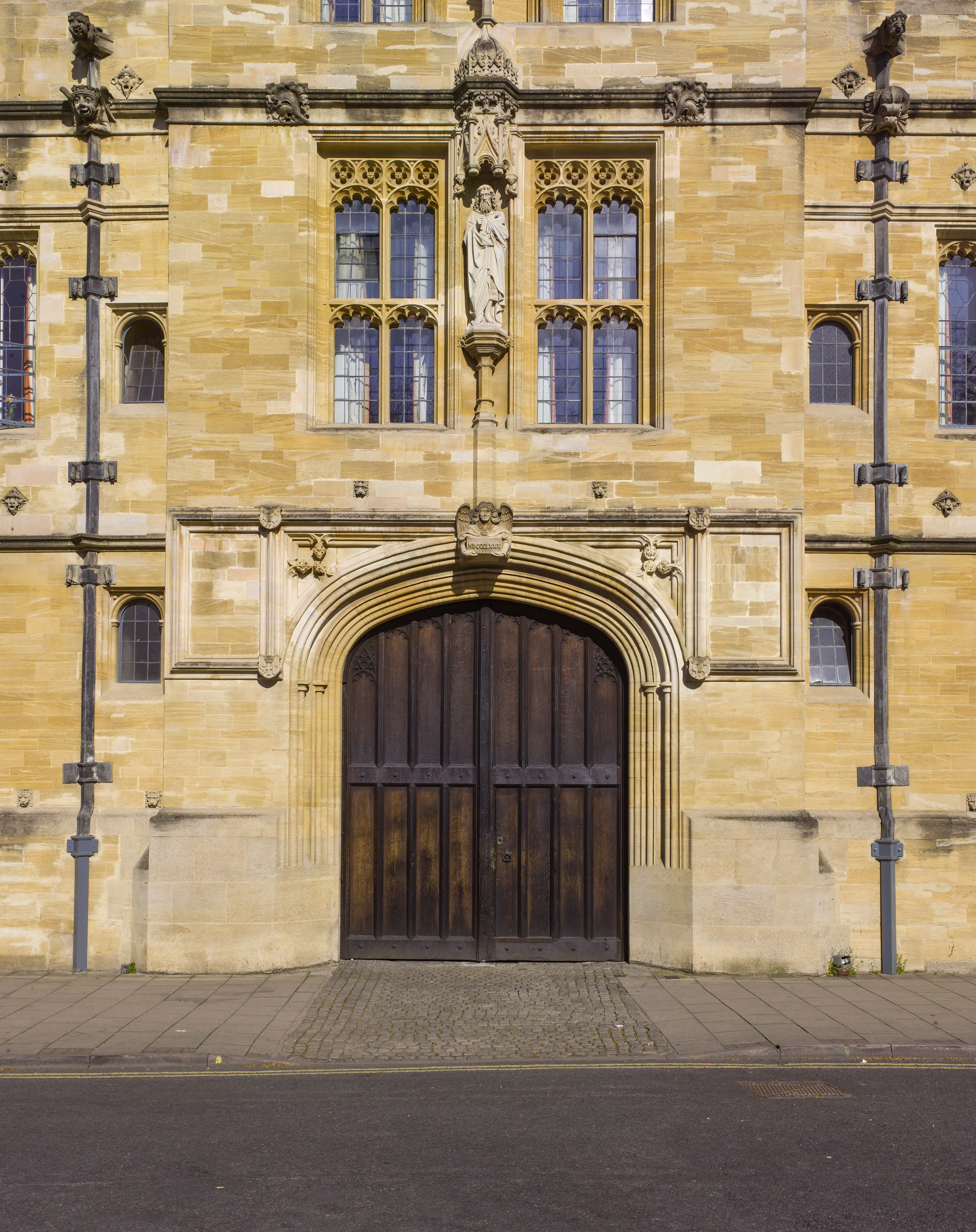 The college's main gate on St Giles': a tall studded oak door set in a pointed stone archway.